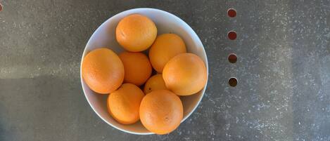 Un bol d’oranges posé sur une surface métallique.