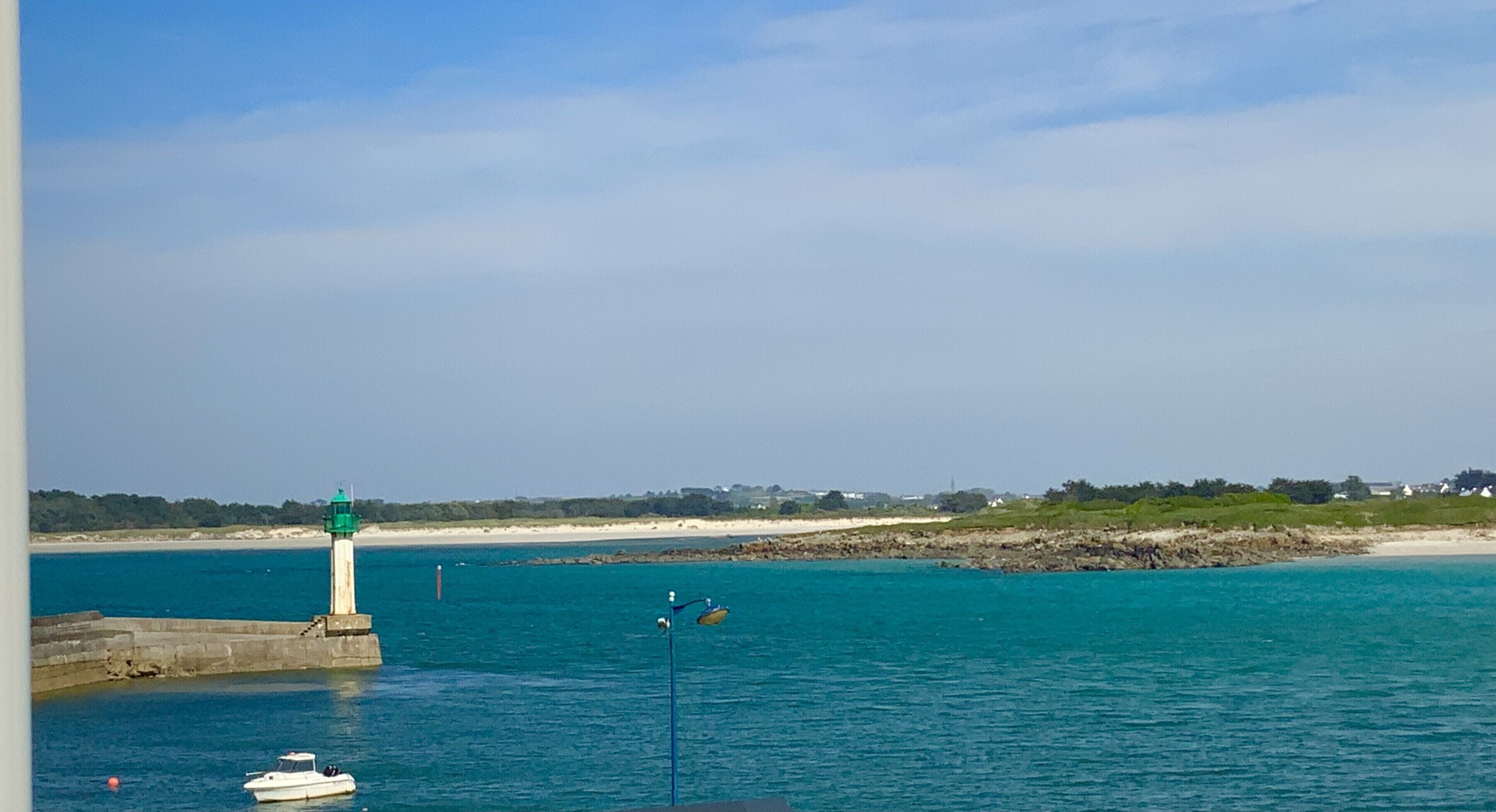 A coastal scene with a lighthouse, a small boat, and a rocky shoreline.