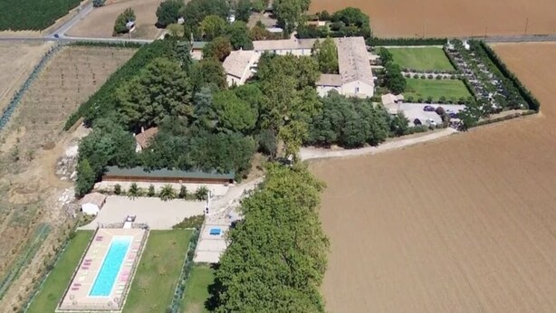 Vista aérea de una propiedad con piscina, varias construcciones y campos aledaños.