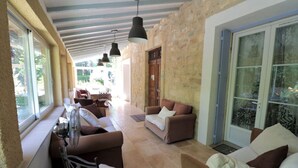 Amplia sala de estar con pared de piedra, puerta corredera de vidrio y varios arreglos de asientos, incluyendo sofás y sillones.