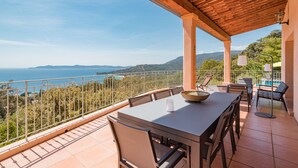 En terrass med ett bord och stolar, med en vacker utsikt över havet och kullarna.