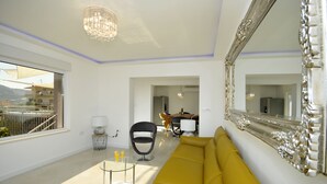 Una sala de estar moderna con un sofá amarillo, un espejo grande y ornamentado, y un candelabro.