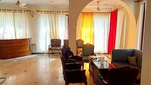 A spacious living room with a wooden coffee table, two armchairs, a sofa, and a TV. - Swiss Cottage (Islamabad)