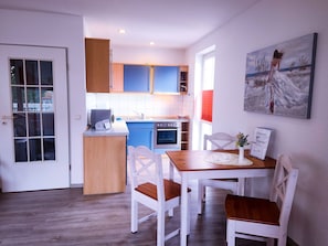 Een moderne keuken met blauwe kastjes, een houten aanrechtblad en een eethoek met witte stoelen en een tafel.