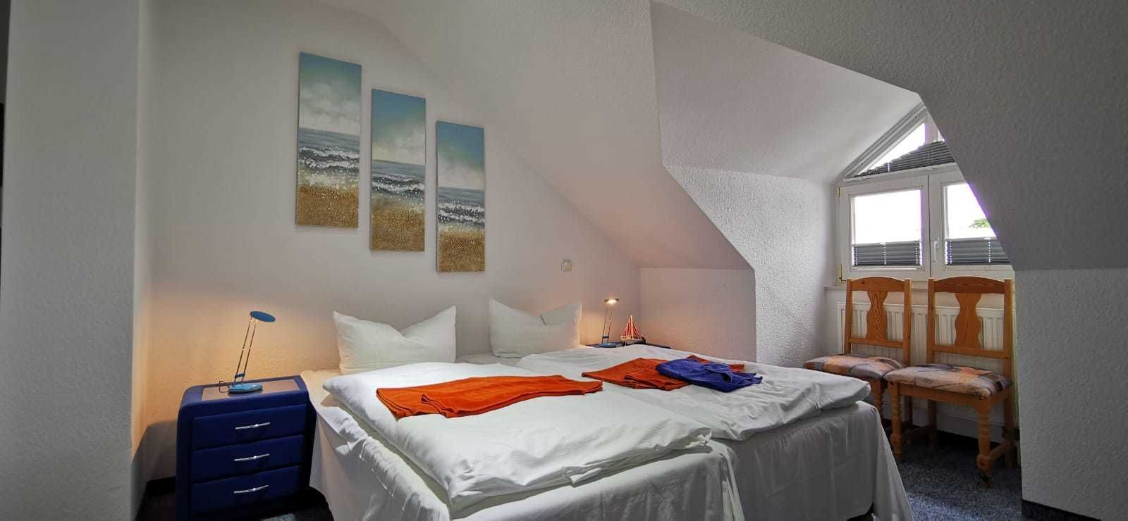 A bedroom with a bed, a desk, a chair, and a window.