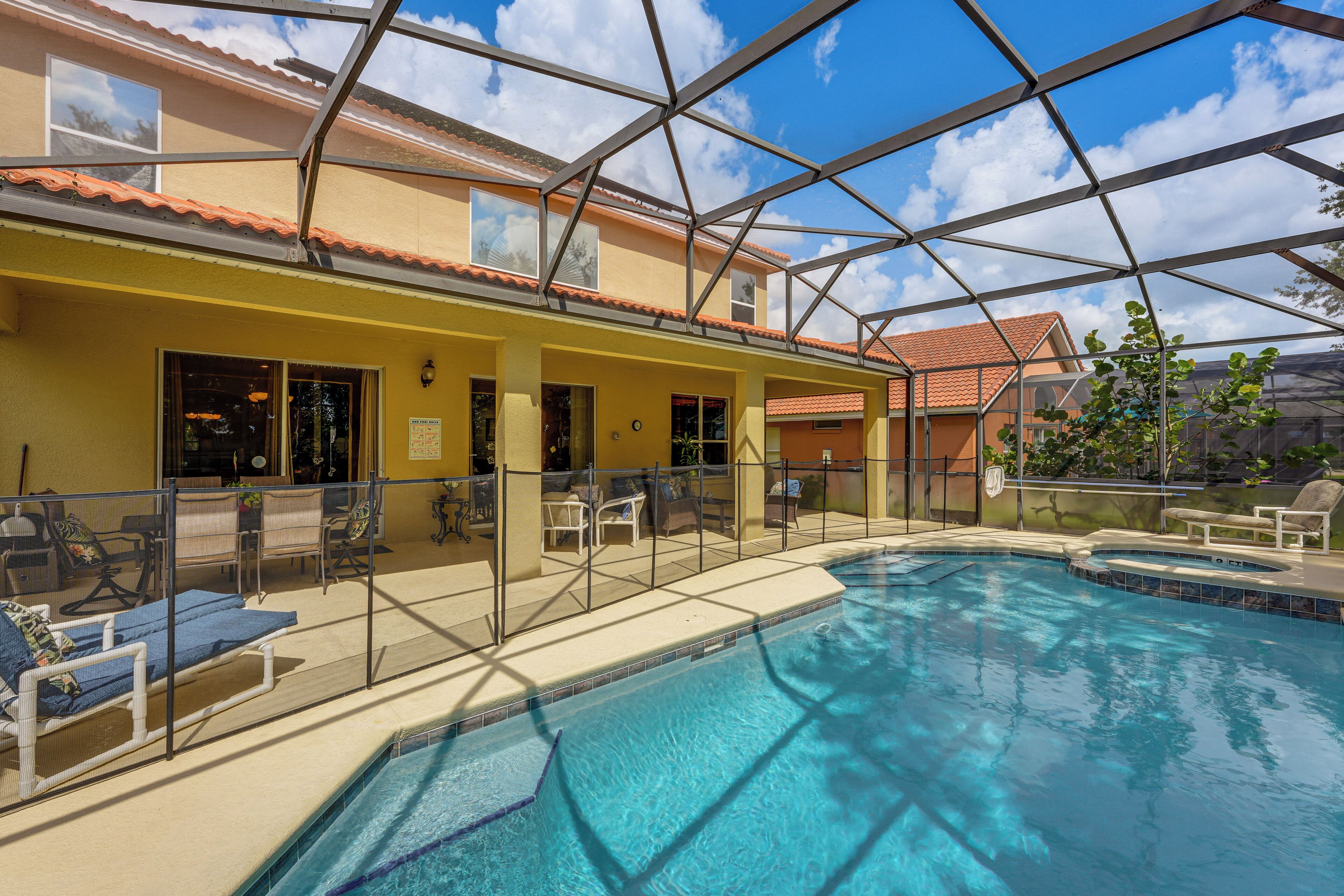 An indoor swimming pool with a glass ceiling, surrounded by lounge chairs and a covered patio area.