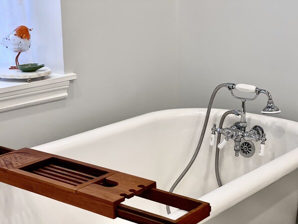 A white bathtub with a wooden tray, a shower head, and a faucet with a hose.