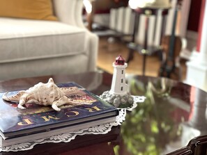 A book titled "The World" on a glass table with a lace doily, a small lighthouse model, and a seashell. - Charlotte's Rose Inn (Charlottetown)