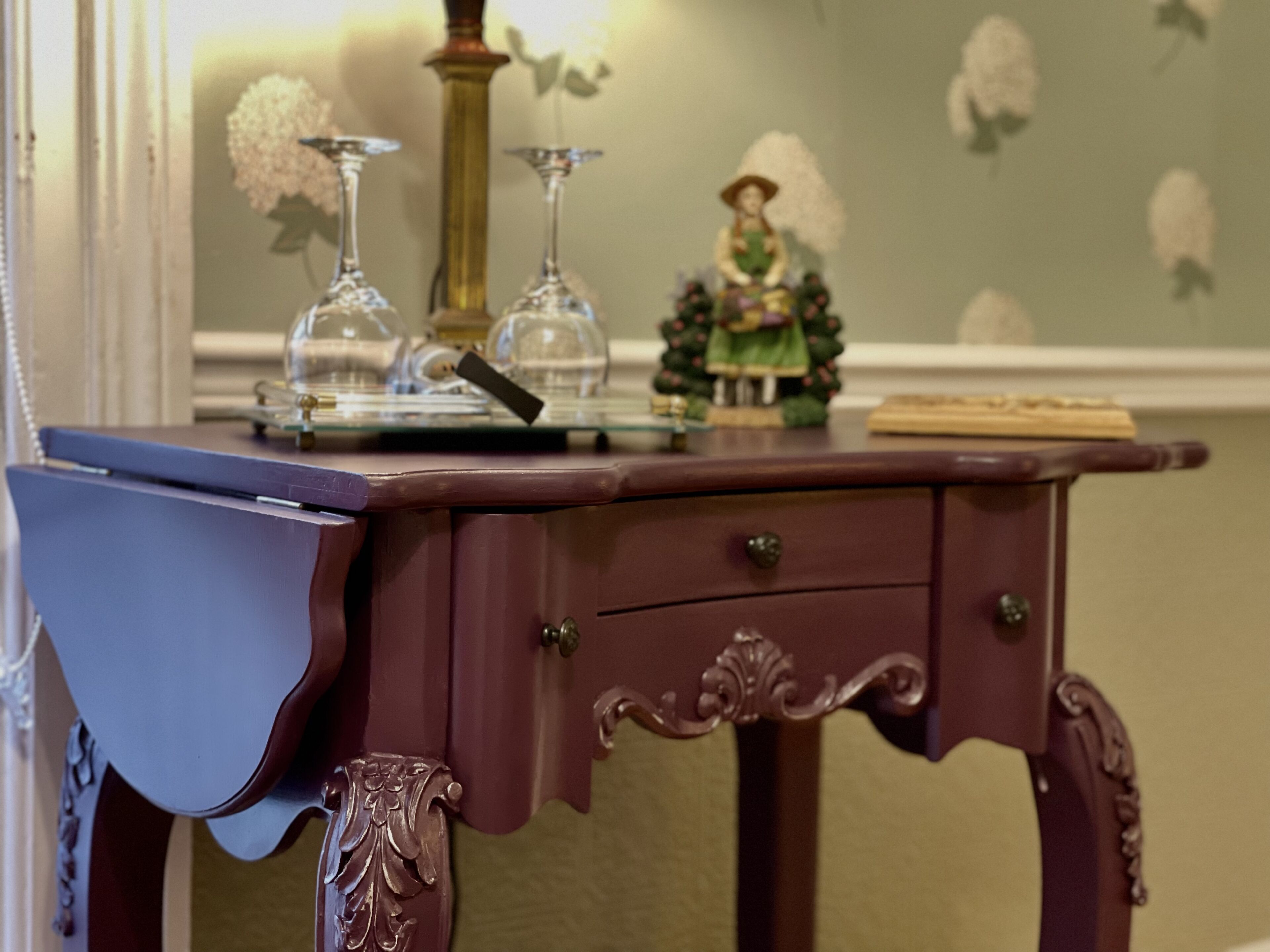Un bureau en bois avec un tiroir, un vase et une petite figurine posés dessus.