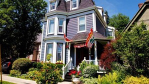 A Victorian-style house with a porch, multiple windows, and a flag. - Charlotte's Rose Inn (Charlottetown)