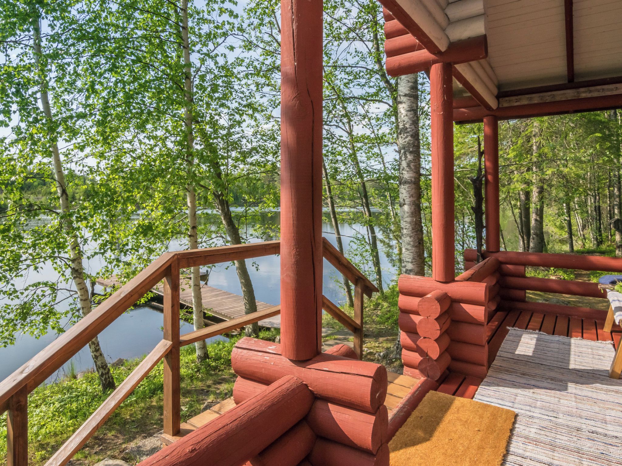 Une terrasse en bois offrant une vue sur un lac et des arbres.