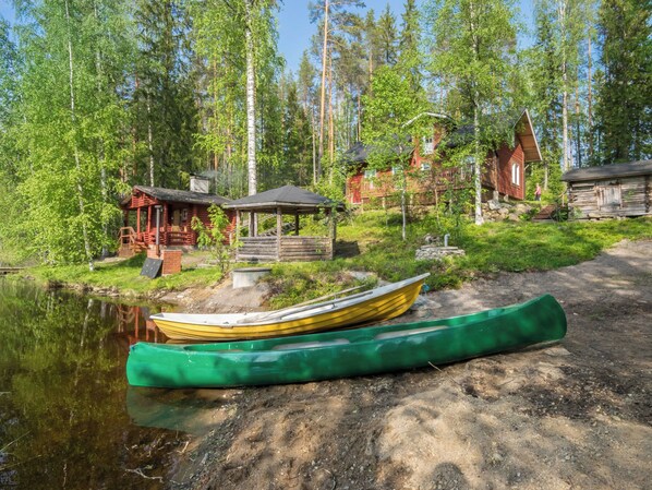 A lakeside cabin with a canoe, surrounded by dense forest.