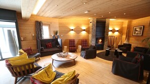 A cozy, well-lit living room with wooden floors and walls, furnished with sofas, armchairs, and a coffee table. - Superb 6-person apartment at the foot of the slopes, in the "Coeur des Loges" residence (Les Menuires)