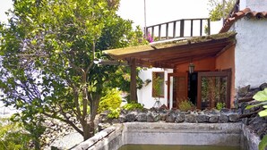 Une maison traditionnelle avec un mur en pierre, une terrasse en bois et un petit étang.