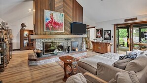 A spacious living room with a fireplace, a television, and a large painting.