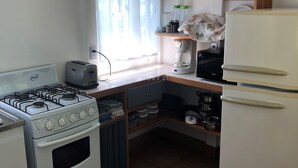 Ett kök med en gasspis, en brödrost, en kaffebryggare och ett kylskåp.