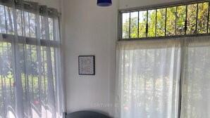 Ett rum med två sängar, ett litet bord och ett fönster med gardiner.