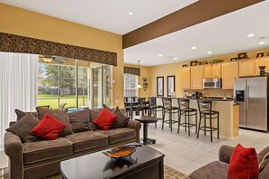 Relax in this inviting living space with a sofa, coffee table, and kitchen bar area.