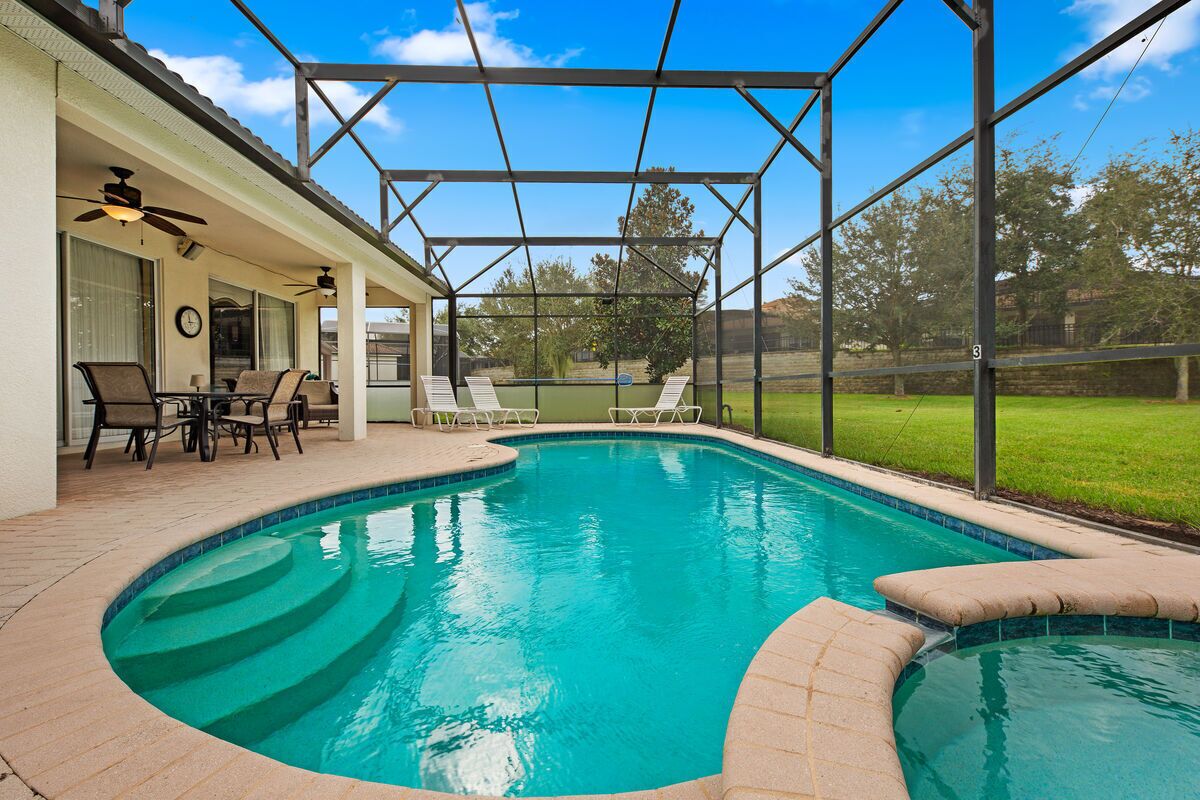 Una piscina con un porche cubierto, mobiliario exterior y vistas del paisaje circundante.