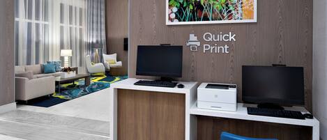 A modern office space with a desk, computer, printer, and a couch in the background.