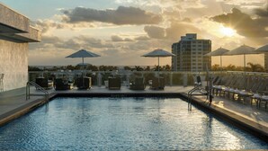 A rooftop pool with lounge chairs and umbrellas, overlooking a cityscape and palm trees. - Courtyard by Marriott Delray Beach (Delray Beach)