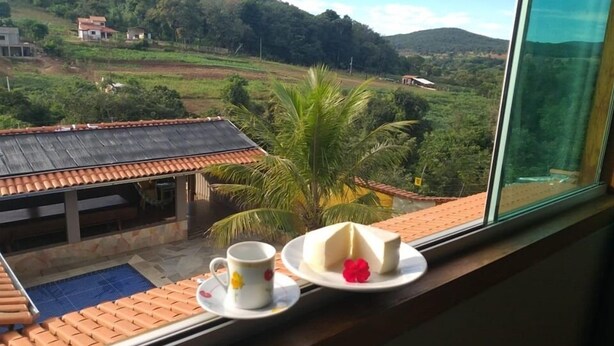 Vista desde una ventana a un paisaje rural con casas, una palmera y un tejado de tejas.