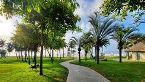 A paved pathway in a park with palm trees and a beach in the background. - Amanda Seaview Resort Apartment (Lingshui)