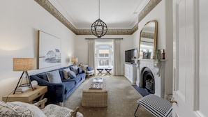 A living room with a sofa, a coffee table, a fireplace, a television, and a large mirror.