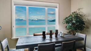Comedor con un gran ventanal que ofrece vistas a un lago y montañas.