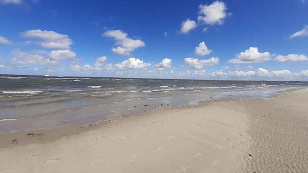 En strand med klart himmel og bølger.