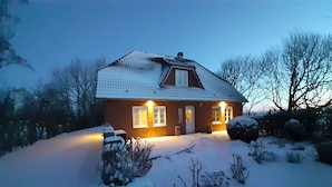 Et toetagers hus med skråt tag, en veranda og en snedækket have.