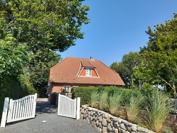 Ein Haus mit rotem Ziegeldach, einer Steinsäule und einem weißen Tor.