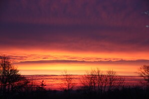 Ein Sonnenuntergang über einer flachen Landschaft mit silhouettierten Bäumen.