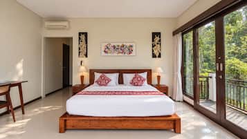 Un dormitorio espacioso con una cama grande, dos mesitas de noche con lámparas, un cabecero de madera y un ventanal con vistas a zonas verdes.