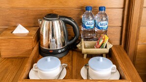 Una bandeja de madera con una tetera, dos botellas de agua, una caja de pañuelos y dos tazas con cucharas.