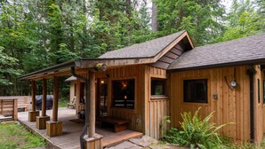 A wooden cabin with a porch, stone pathway, and a small garden area. - Cozy cabin in the Woods, Hot tub, secluded, walk to ZigZag River ! (Rhododendron)