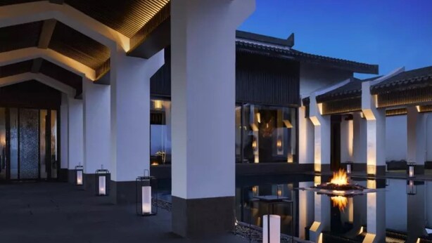 Un edificio moderno con patio central, con una chimenea y faroles.