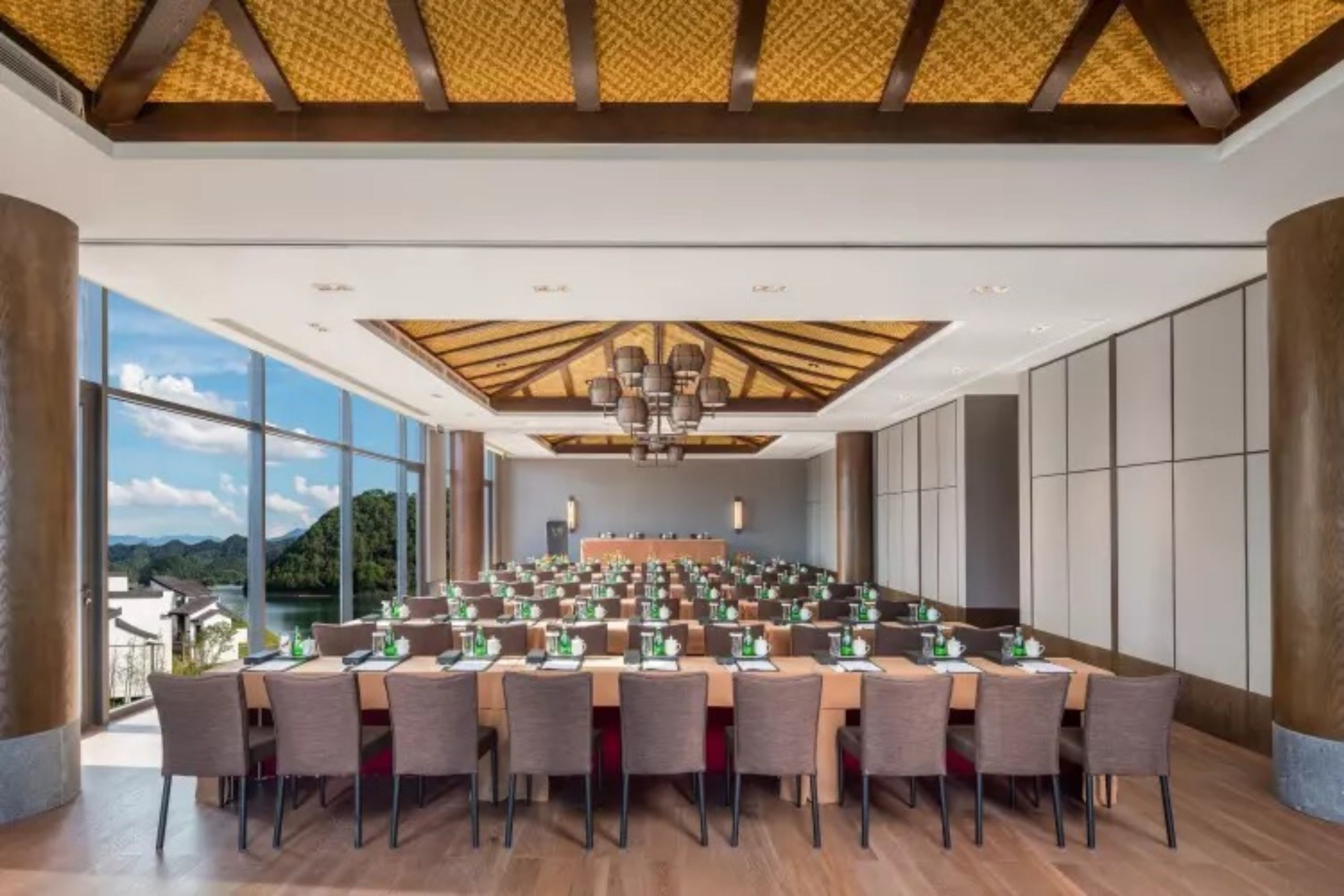 Un salón de conferencias con una larga mesa, sillas y vistas al exterior.