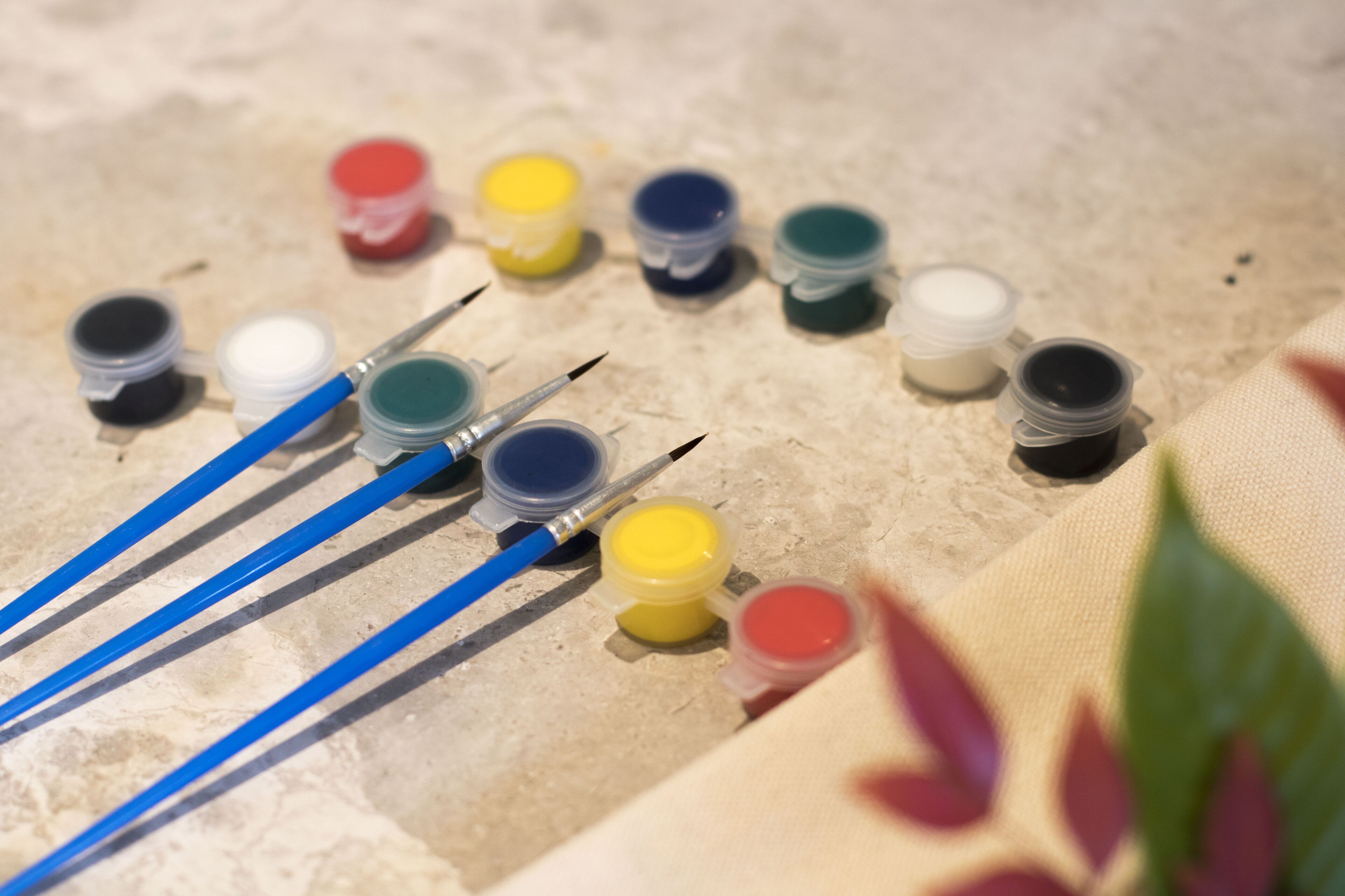 Un conjunto de pinceles y pequeños recipientes de pintura sobre una superficie texturizada.