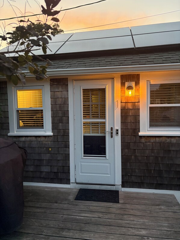 A house with a white door, two windows with blinds, and a small porch with a doormat.