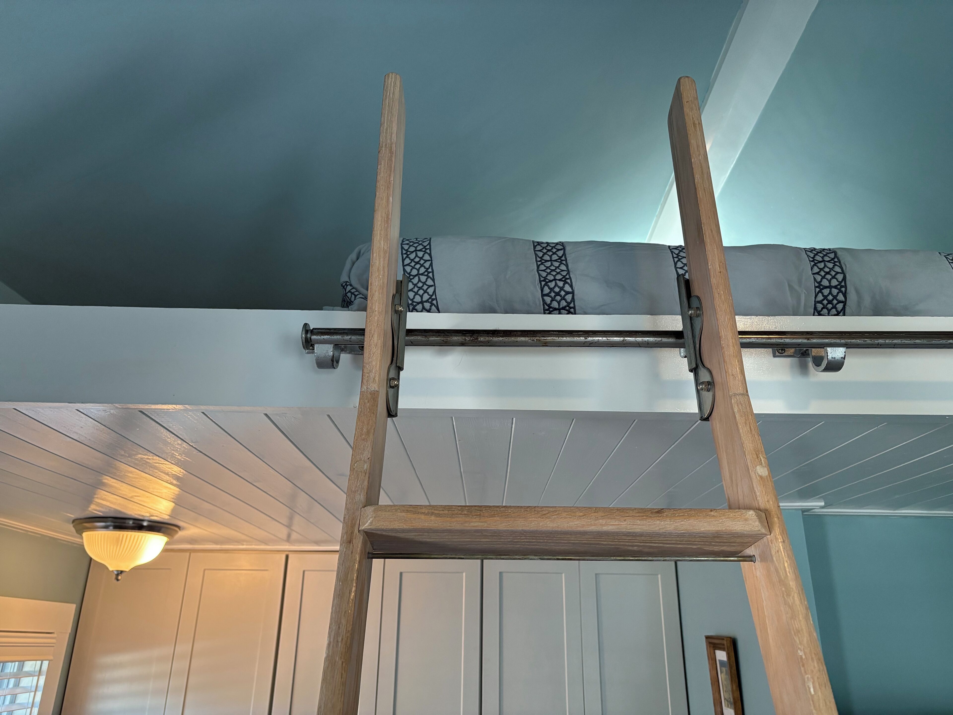En trætrakasse der fører op til et loft med en lampe og en dør i baggrunden.