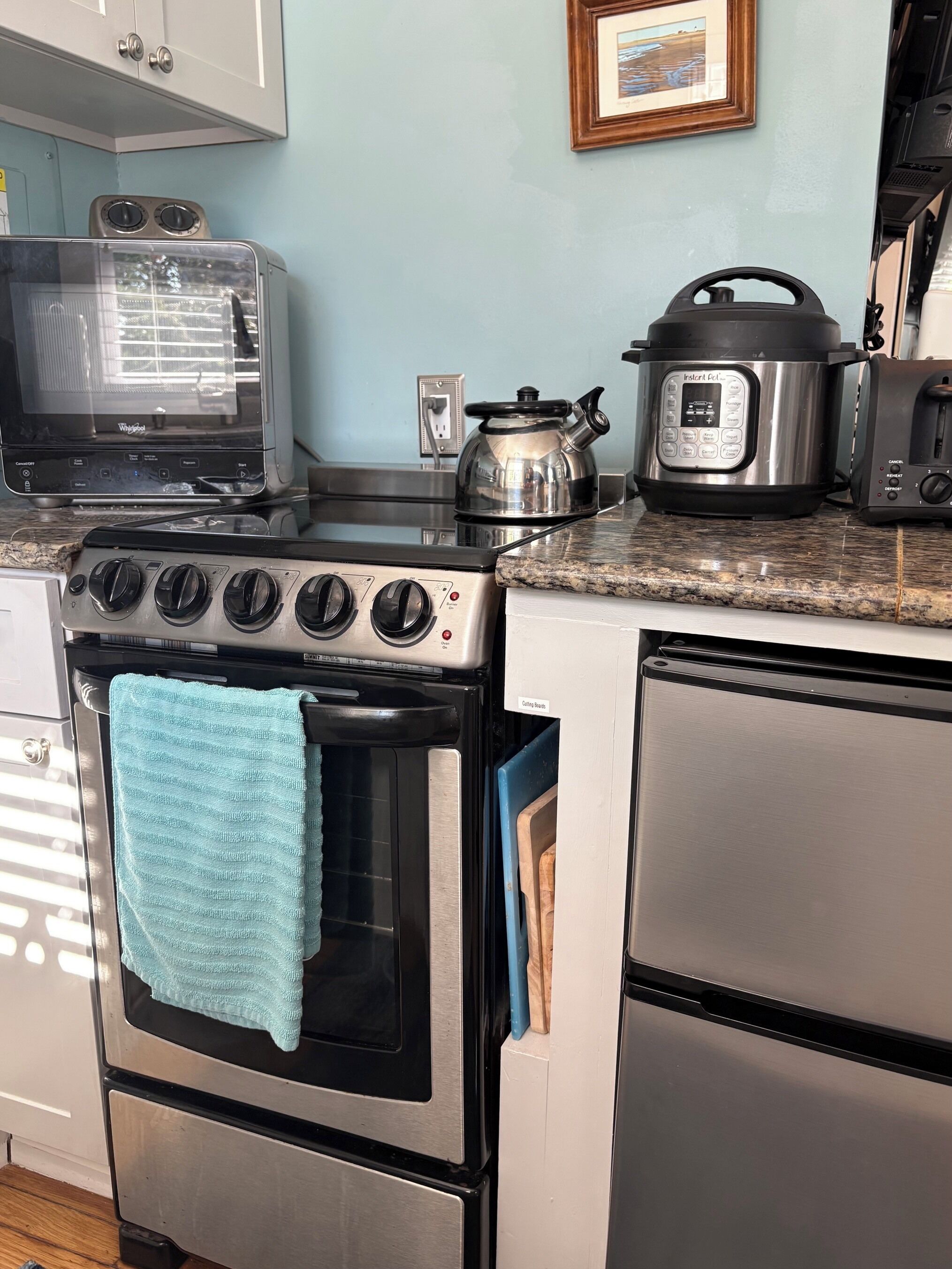 A kitchen with a stove, oven, microwave, toaster, kettle, and a slow cooker.