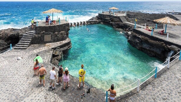Un espace piscine avec une eau d’un bleu limpide, des marches en pierre et des parasols.