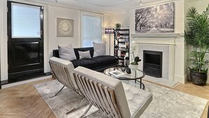A living room with a black sofa, a glass coffee table, and a fireplace. - Heated Pool Access | 5*Clean | Flex Cancelation (Savannah)