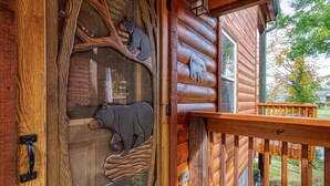 A wooden cabin with a bear-themed door and a welcome sign. - Pigeon Forge River Front Cabin- Fishing Year Round-firepit with seating and Hottub (Pigeon Forge)