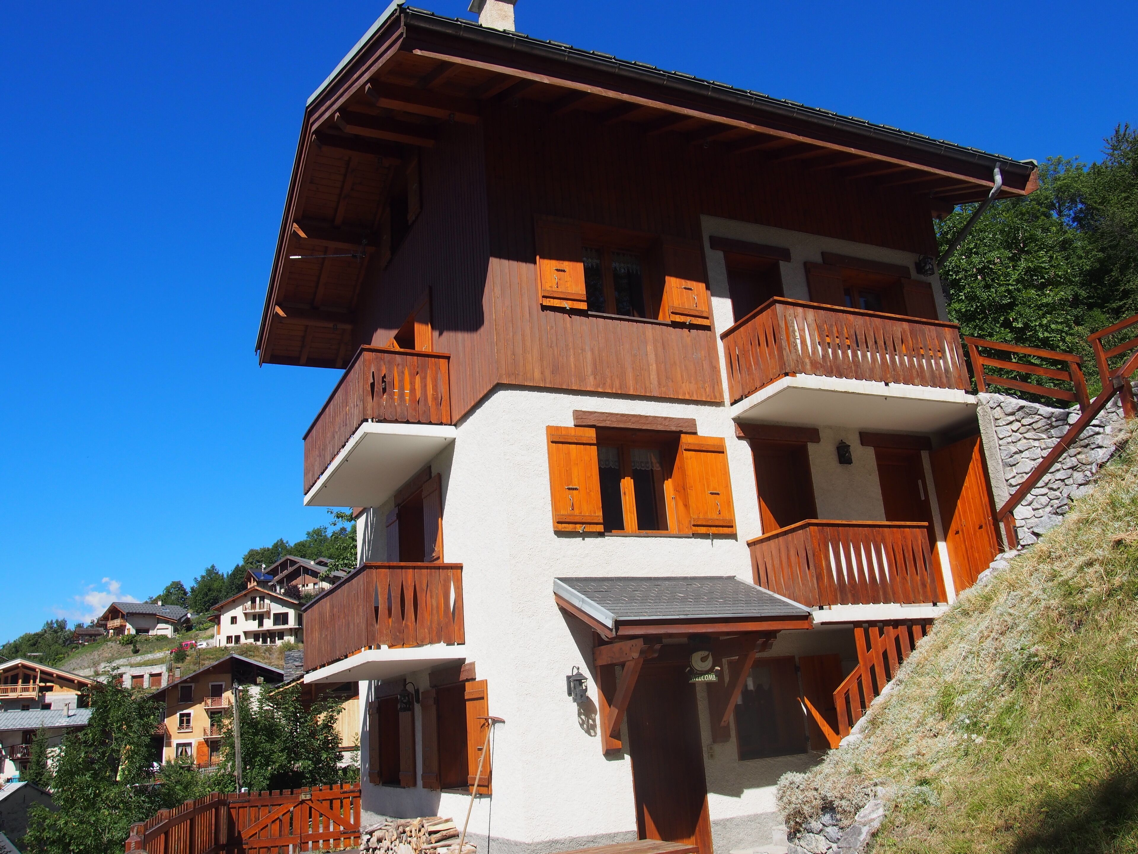 A multi-story chalet with wooden balconies and a stone staircase.