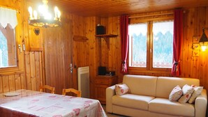 Ein gemütliches Holzhaus mit Esstisch, Sofa und Fernseher.