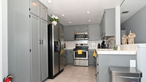 Una cocina moderna con armarios grises, electrodomésticos de acero inoxidable y piso de baldosas.