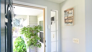 Un pasillo con una puerta que da a una habitación, una planta pequeña y un letrero en la pared con un mensaje.