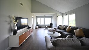 Una sala de estar moderna con un televisor de pantalla plana, un sofá, una mesa de centro y un comedor.